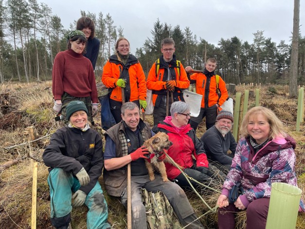 A group of people working outside in a woodland.